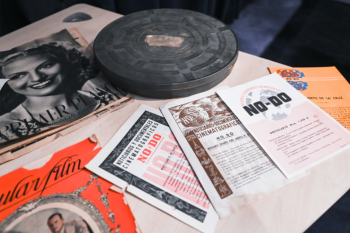 Bobina y documentos del NO-DO en una mesa, con folletos y material de archivo de la Filmoteca Española.